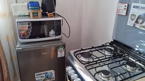 A kitchen with a microwave, a refrigerator, and a gas stove. - Cozy studio with WIFI &Parking in South B (Nairobi)