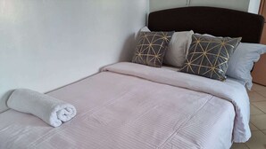 A neatly made bed with a pink bedspread and a rolled white towel. - Cozy studio with WIFI &Parking in South B (Nairobi)