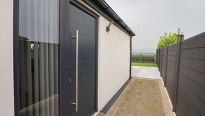 Een modern gebouw met een grote garagepoort, een verhard pad en uitzicht op een groen landschap.