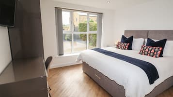 Une chambre avec un grand lit, un bureau et une fenêtre donnant sur un paysage verdoyant.