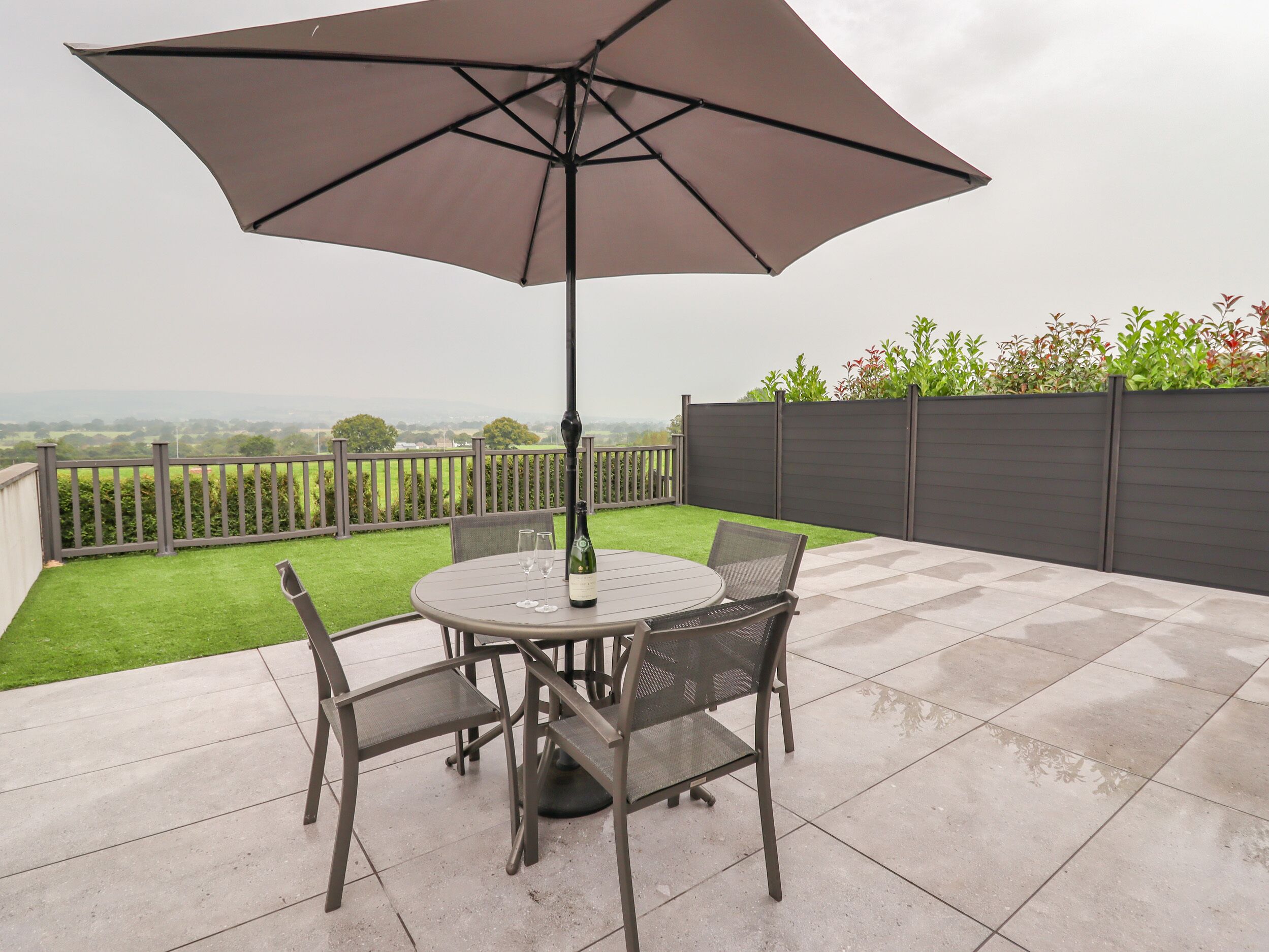 A patio with a round table, two chairs, and a large umbrella.