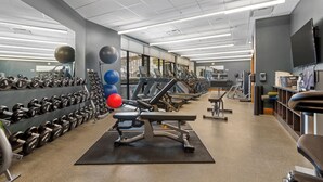 Academia com esteiras, halteres e bolas de exercício.