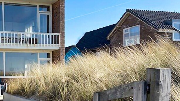 A two-story building with a balcony and a wooden fence. - Lovely apartment in Bergen aan Zee (Bergen aan Zee)