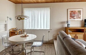Relax in this inviting living room with a round dining table, comfortable sofa, and a cozy reading nook.