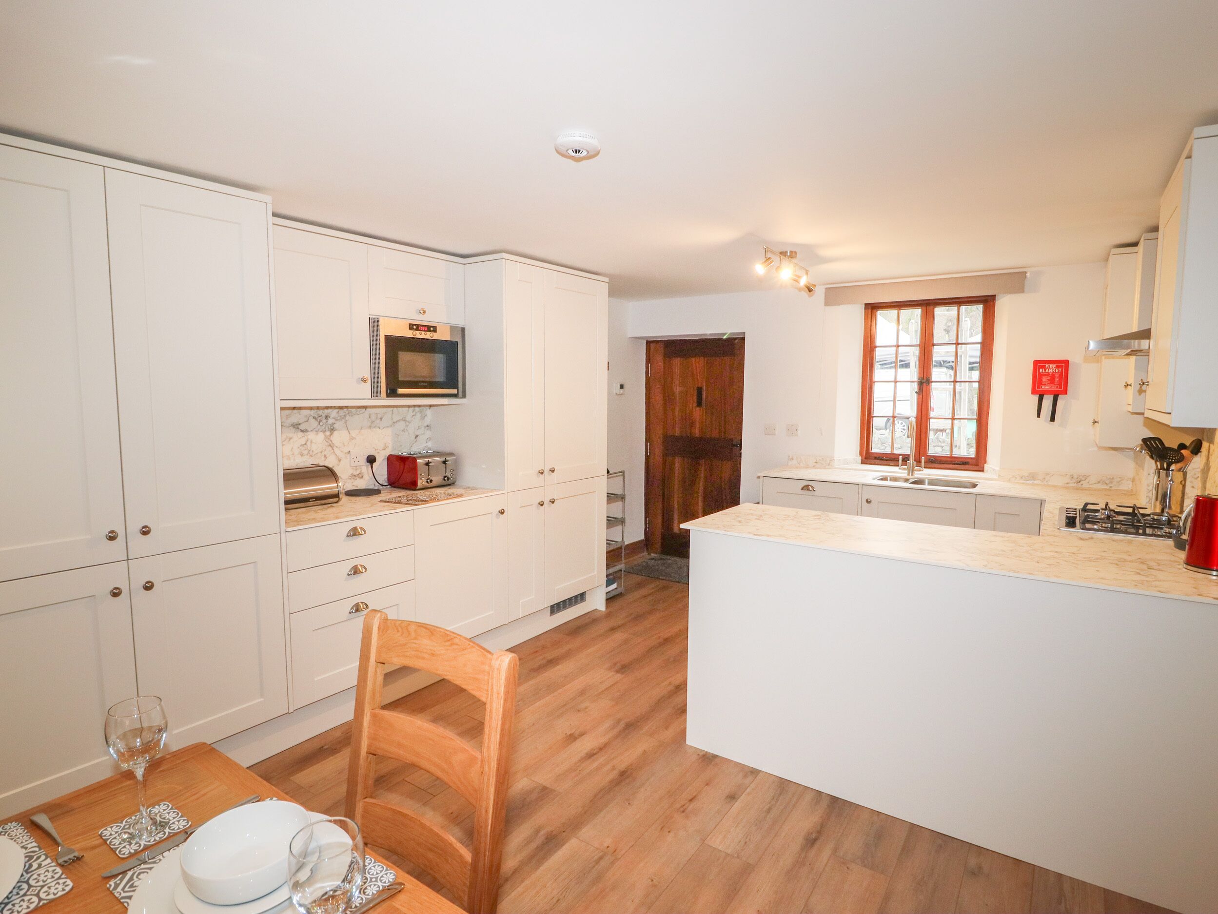 A modern kitchen with white cabinets, a wooden dining table, and a large island.