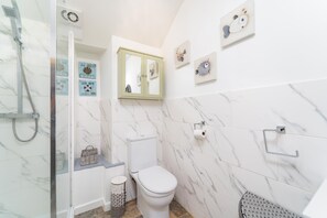 Een badkamer met een douchecabine, toilet en een wastafel met spiegel.