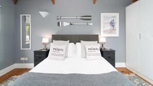 Une chambre à coucher comprenant un lit, deux tables de chevet, une commode, un miroir, un tableau encadré et une armoire.