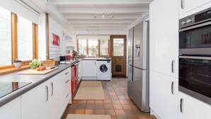 Une cuisine moderne avec des meubles blancs, un four encastré et un lave-linge.