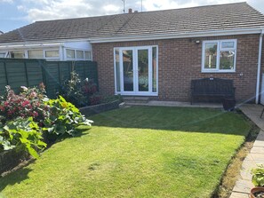 A residential house with a well-maintained lawn, a brick exterior, and a sliding glass door.
