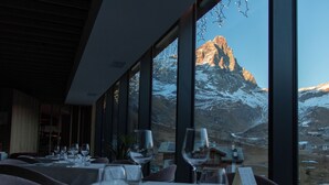 Een restaurant met gedekte tafels, grote ramen met uitzicht op met sneeuw bedekte bergen.