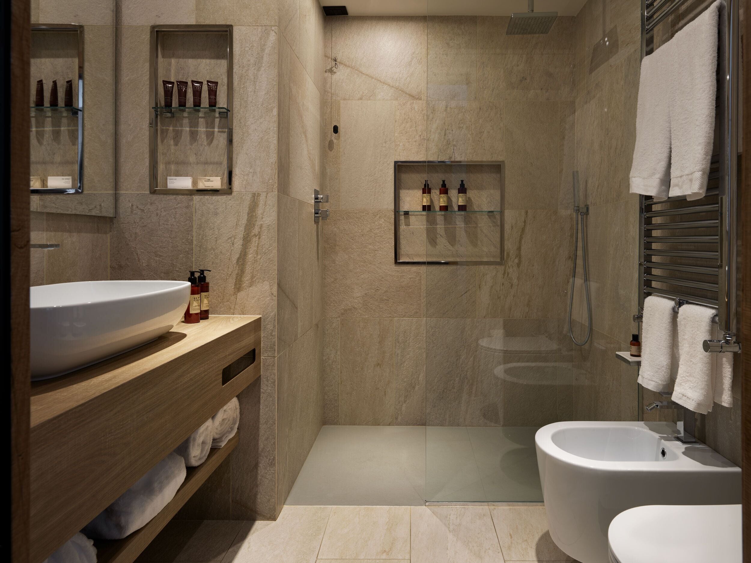 A modern bathroom with a large sink, a bidet, and a glass-enclosed shower area.
