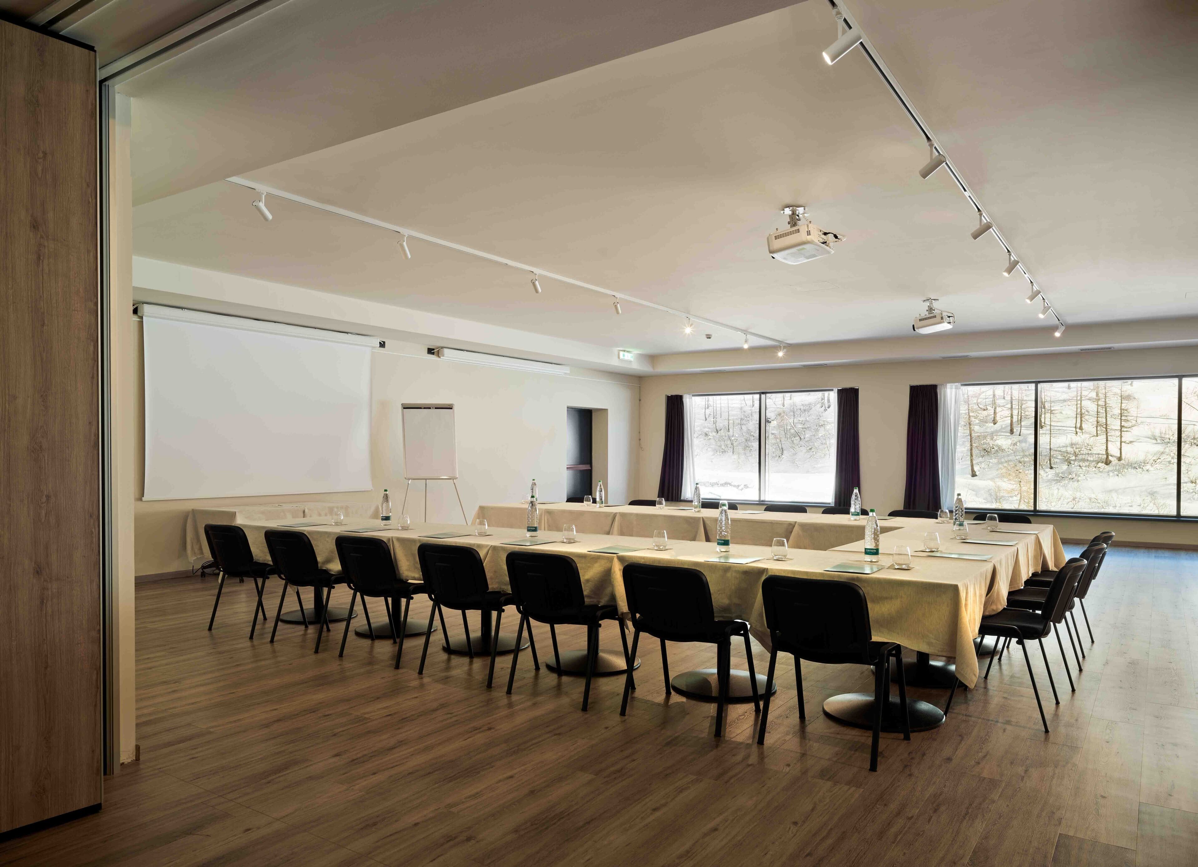 A conference room with a long table, chairs, a whiteboard, and a projector.