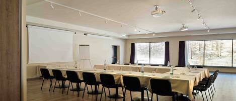 A conference room with a long table, chairs, a whiteboard, and a projector.