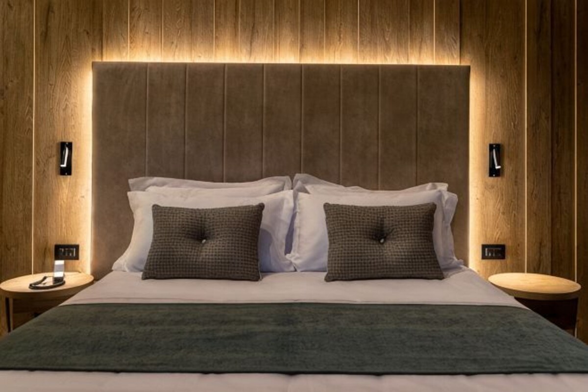 Ein Bett mit Holz-Kopfteil, zwei Nachttische und eine grüne Tagesdecke.
