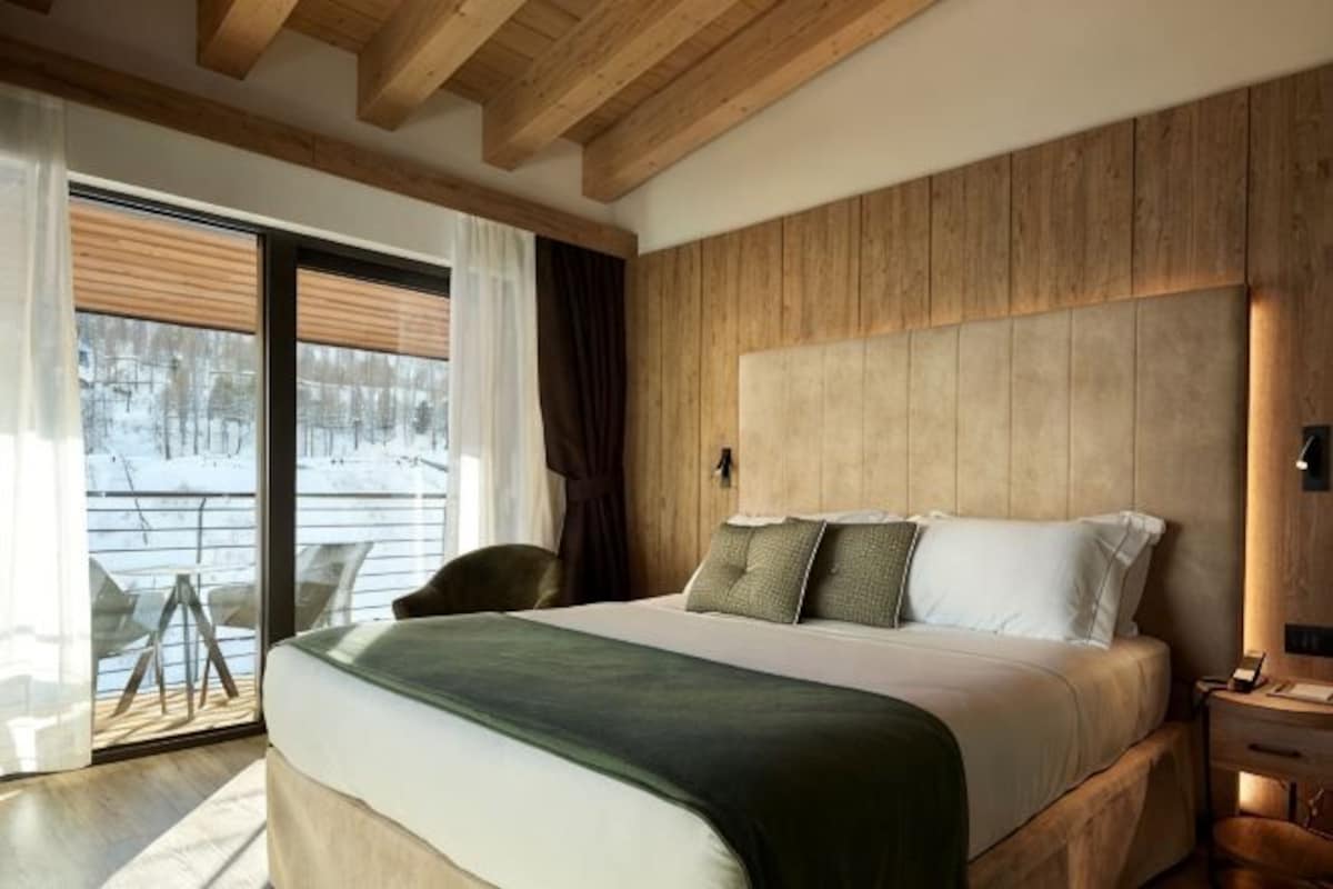 Un dormitorio con una cama grande, cabecera de madera y vistas a un paisaje nevado.