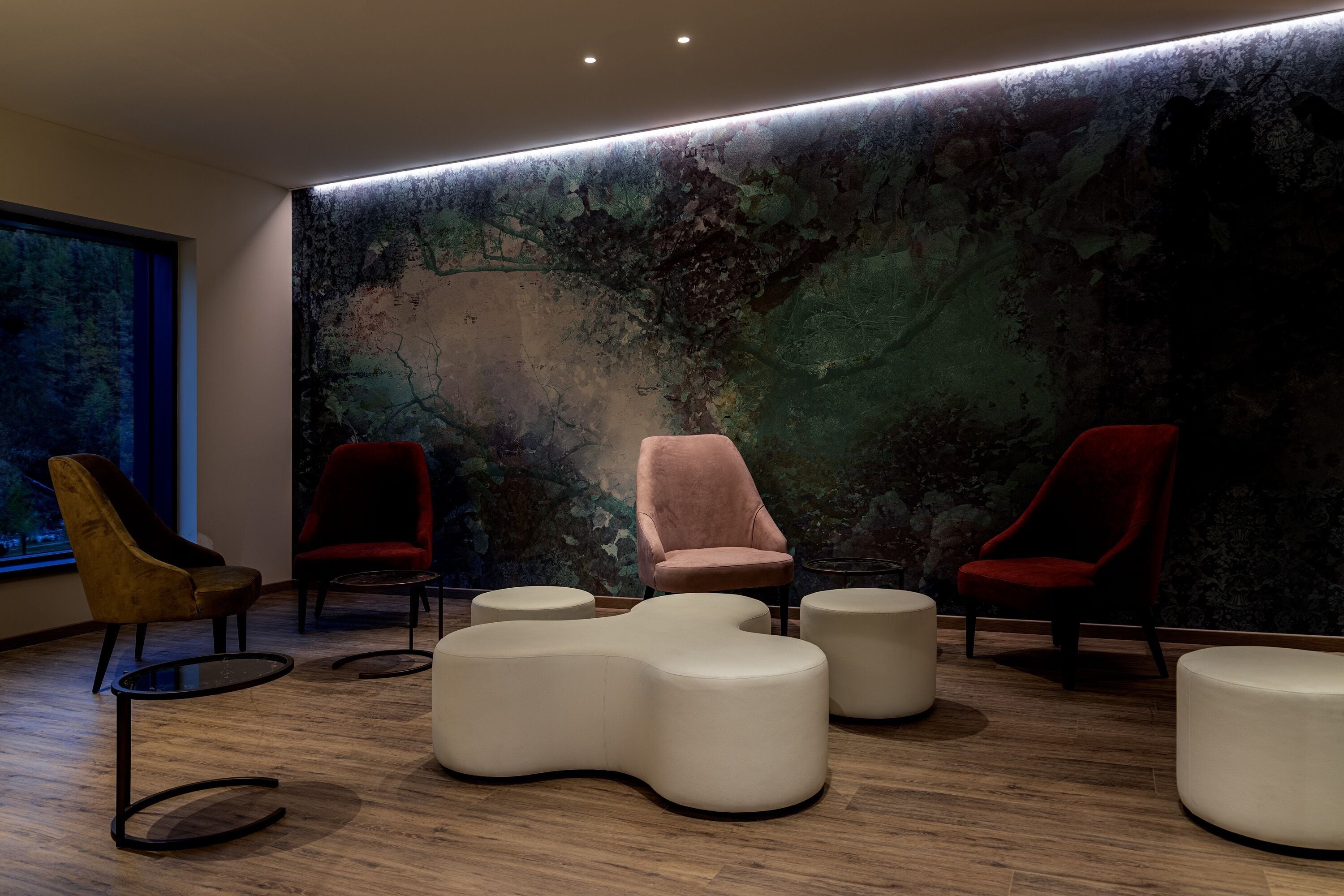 A modern lounge area with a large abstract mural, plush seating, and a wooden floor.