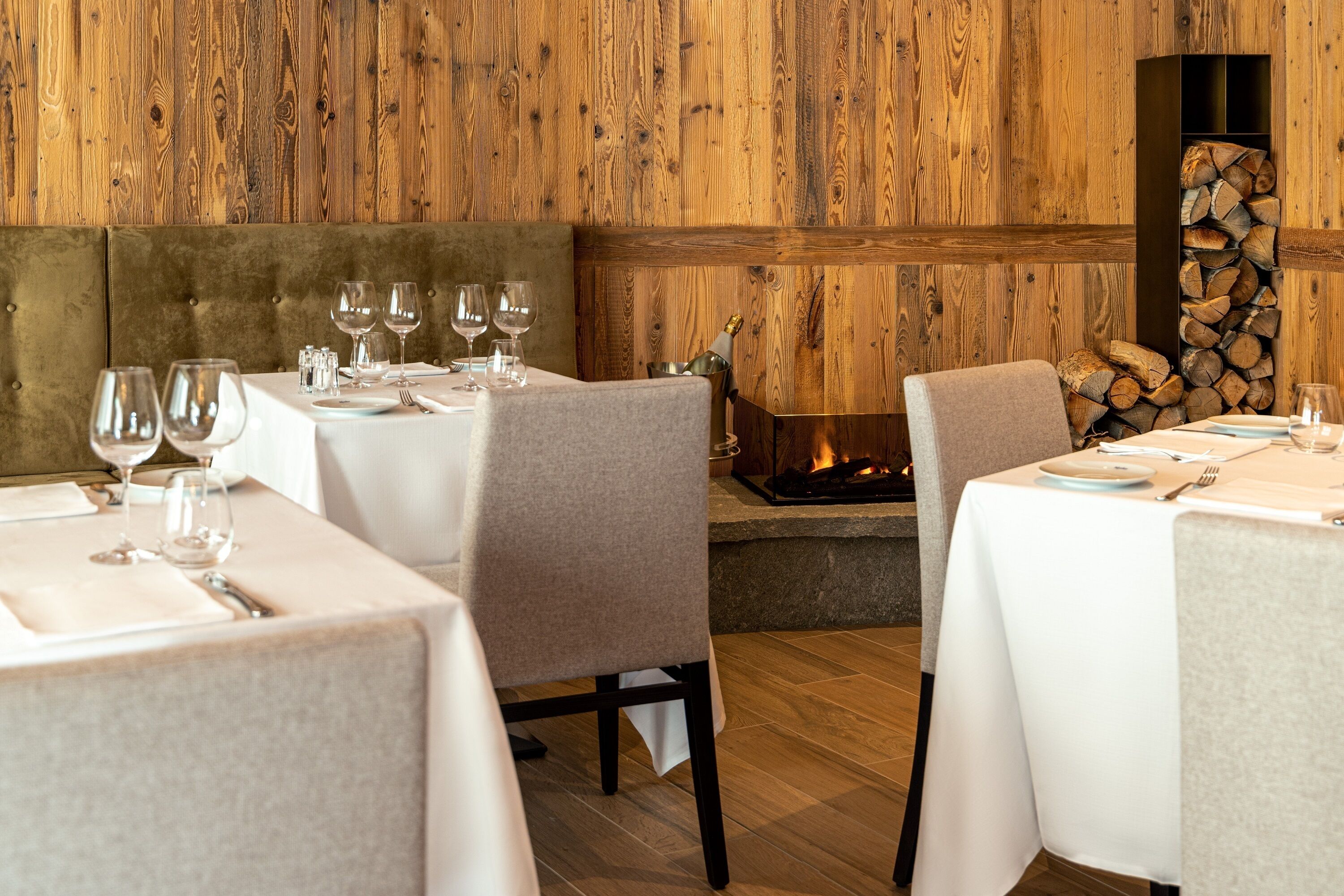 A restaurant with wooden walls, cushioned booths, and a fireplace.