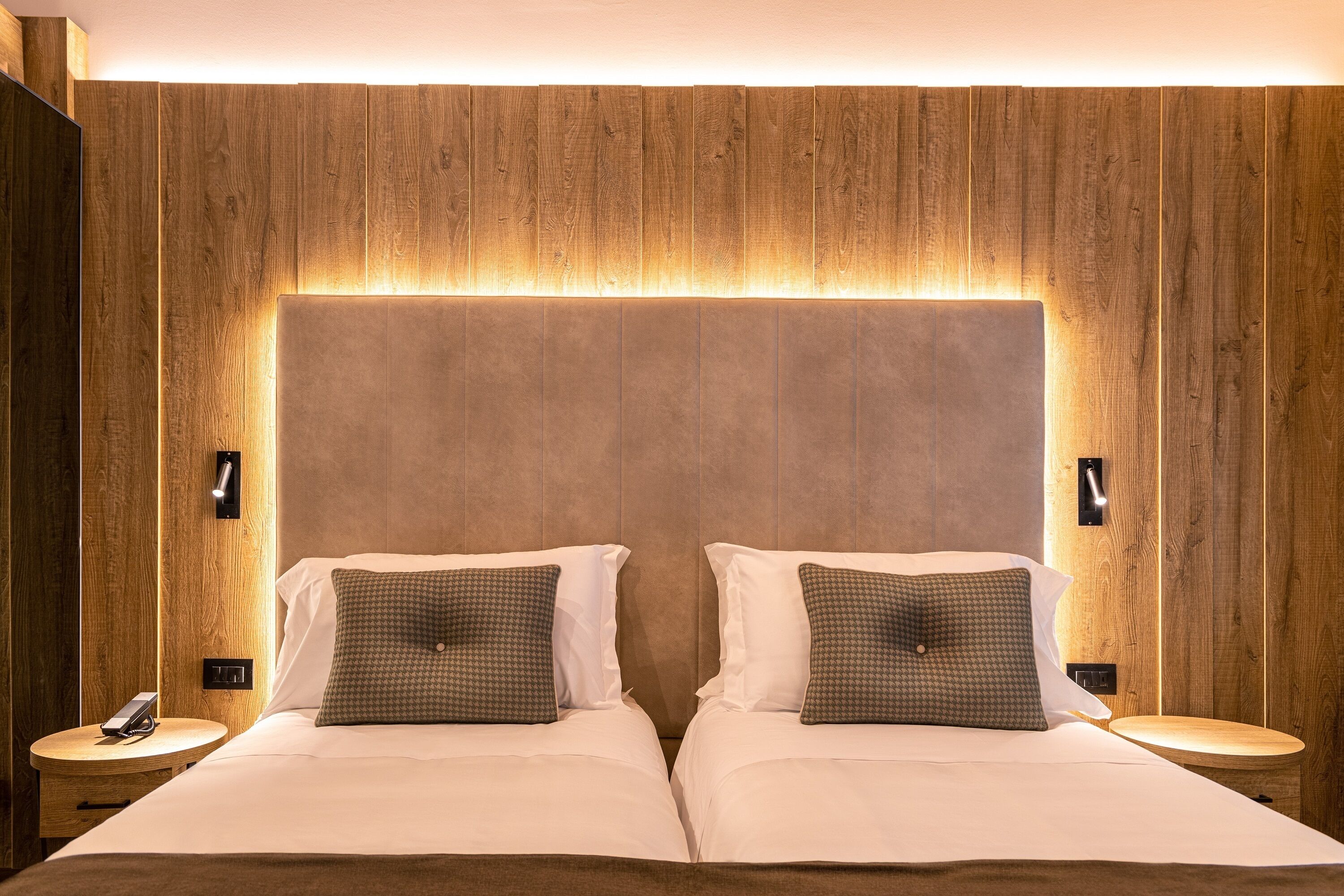 A double bed with a wooden headboard and bedside lamps.