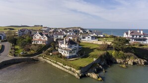 Een kustdorpje met huizen langs de waterlijn, een stenen muur en een helder uitzicht op de zee.