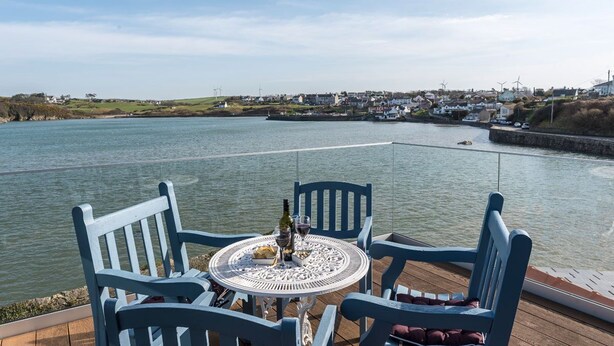 Een tafel met stoelen aan het water, met uitzicht op een stad met huizen en windturbines.