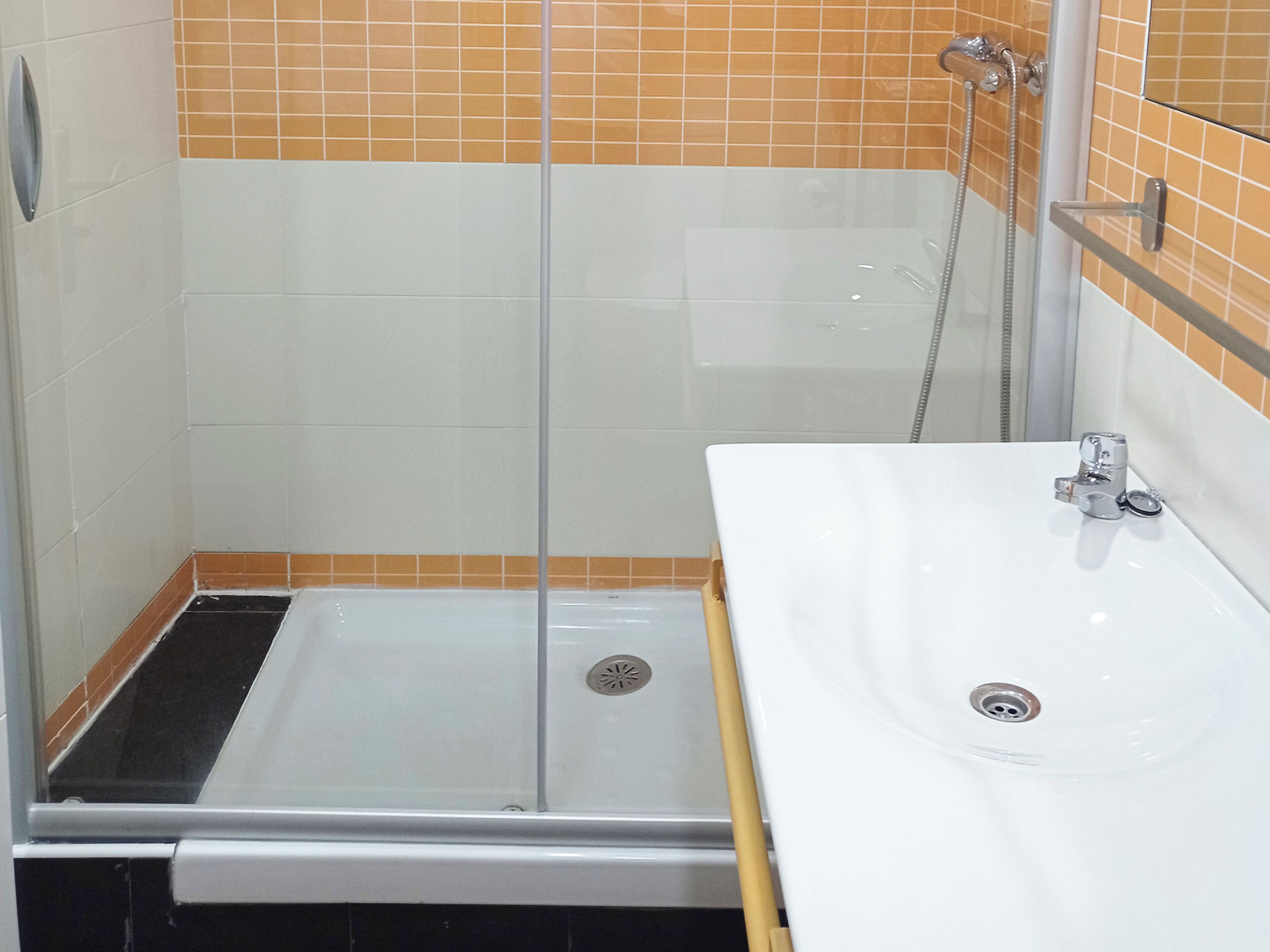 A bathroom with a glass-enclosed shower, a white sink, and tiled walls.