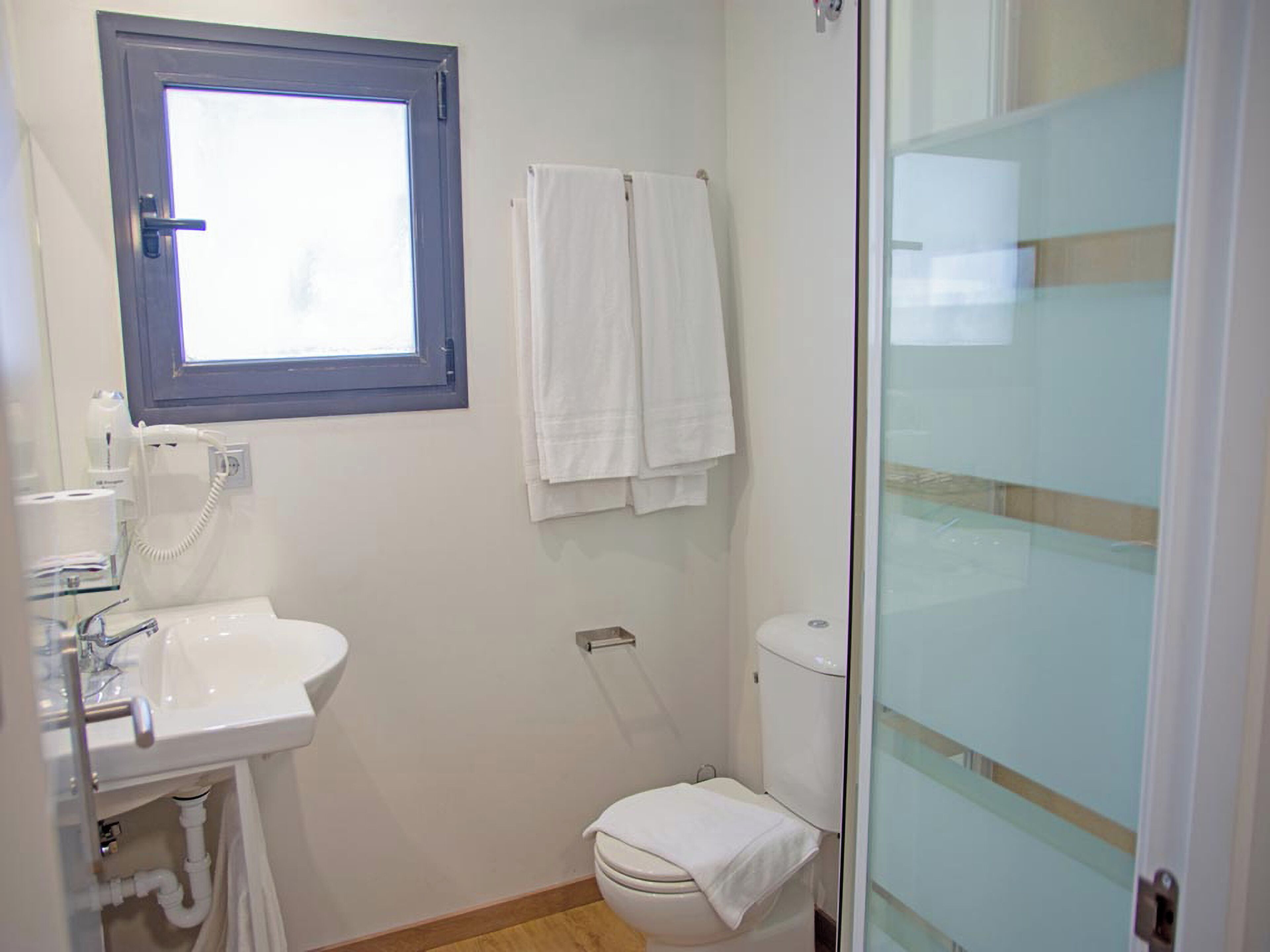 A bathroom with a white sink, a toilet, and a glass shower enclosure.