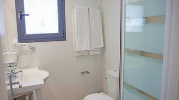 A bathroom with a white sink, a toilet, and a glass shower enclosure.