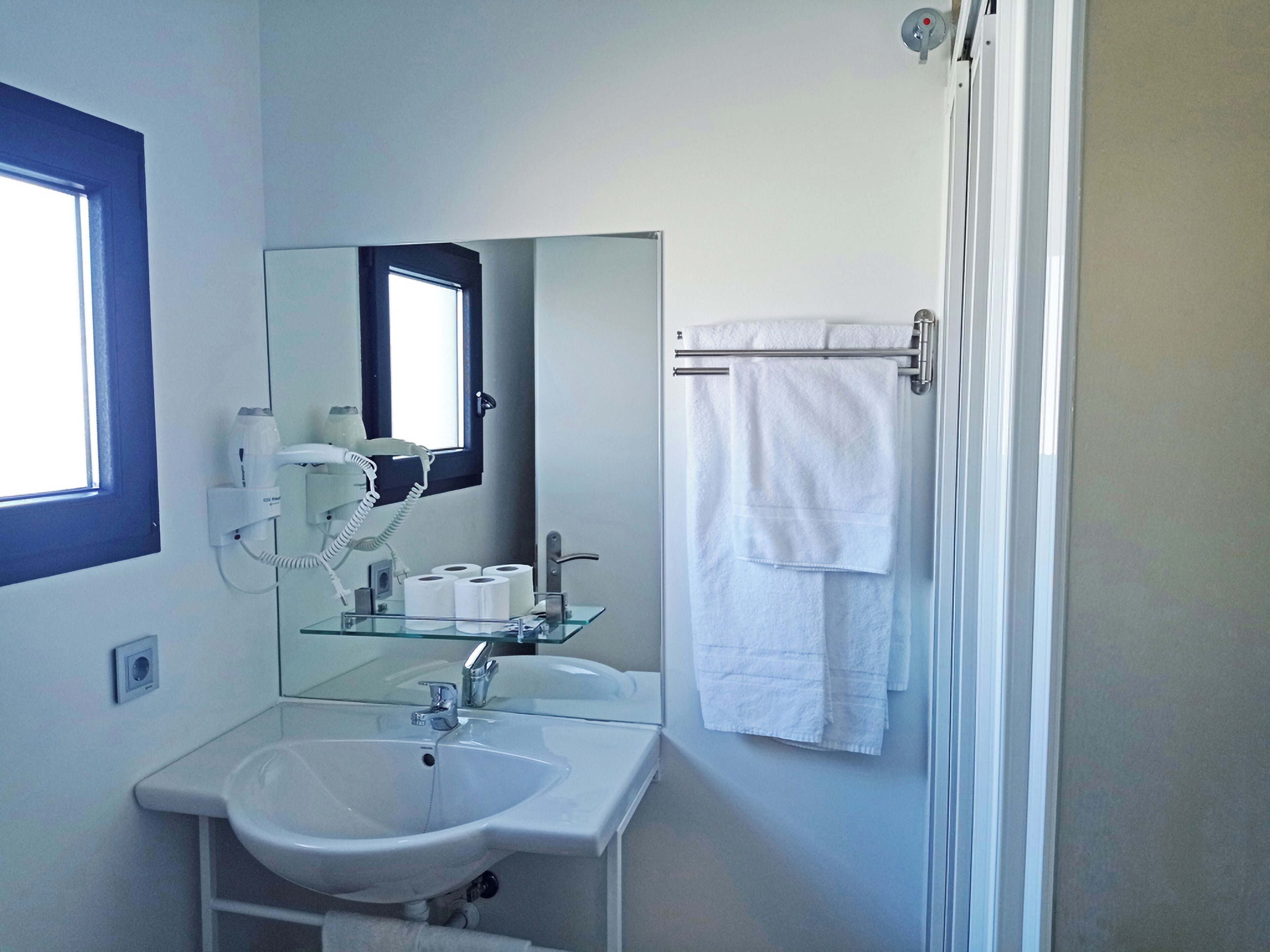 Un bagno con lavandino, specchio e porta asciugamani.