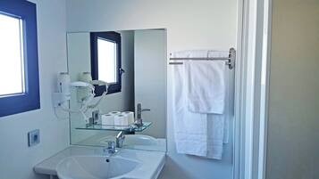 Un bagno con lavandino, specchio e porta asciugamani.