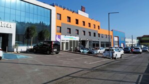Un bâtiment moderne avec une façade en verre, une enseigne indiquant « Apartamentos 3000.com », et plusieurs voitures garées devant.