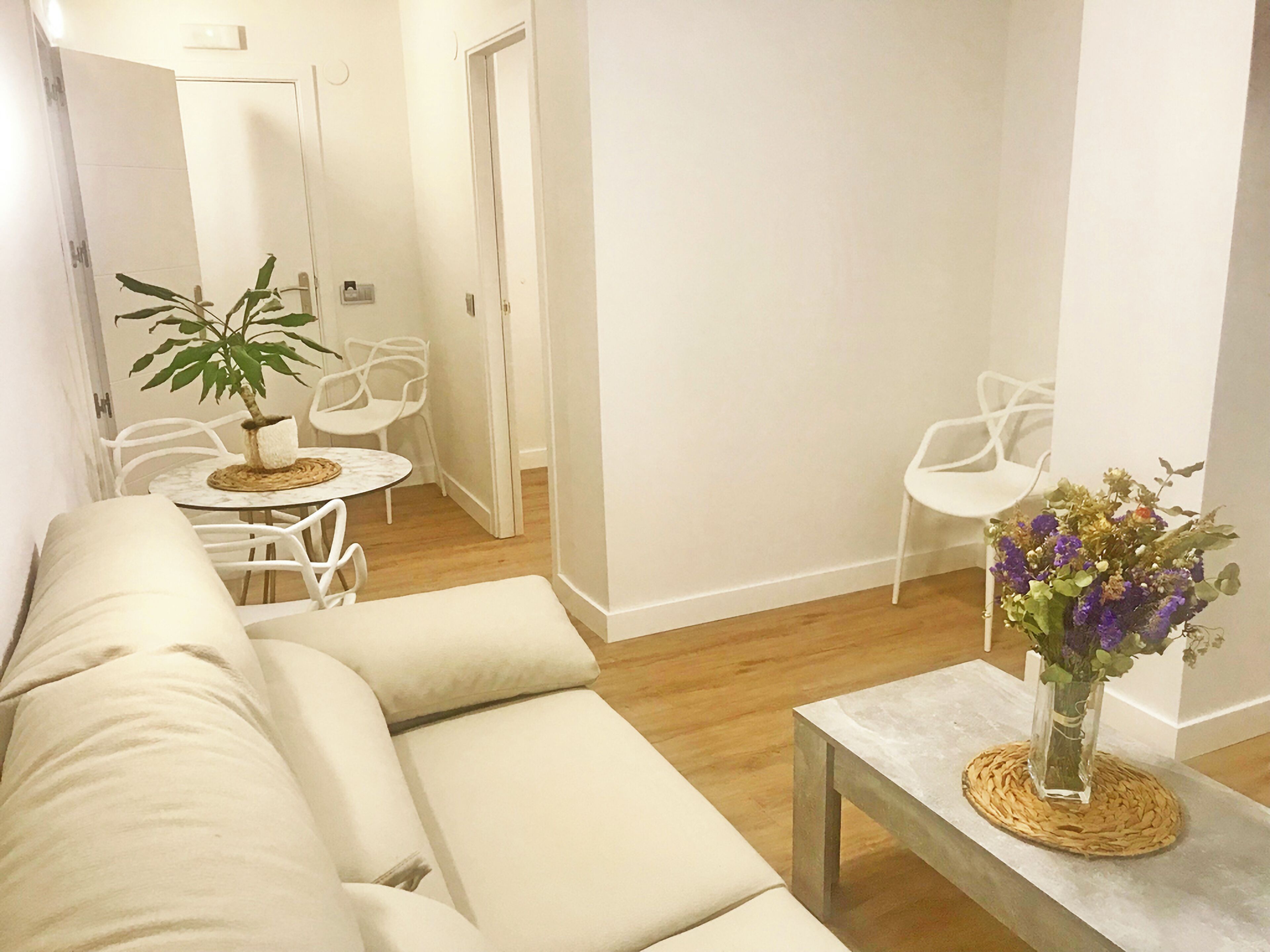 Un salon moderne avec un canapé beige, une petite table ronde et une plante en pot.