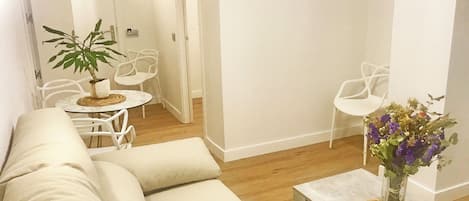 A modern living room with a beige sofa, a small round table, and a potted plant.