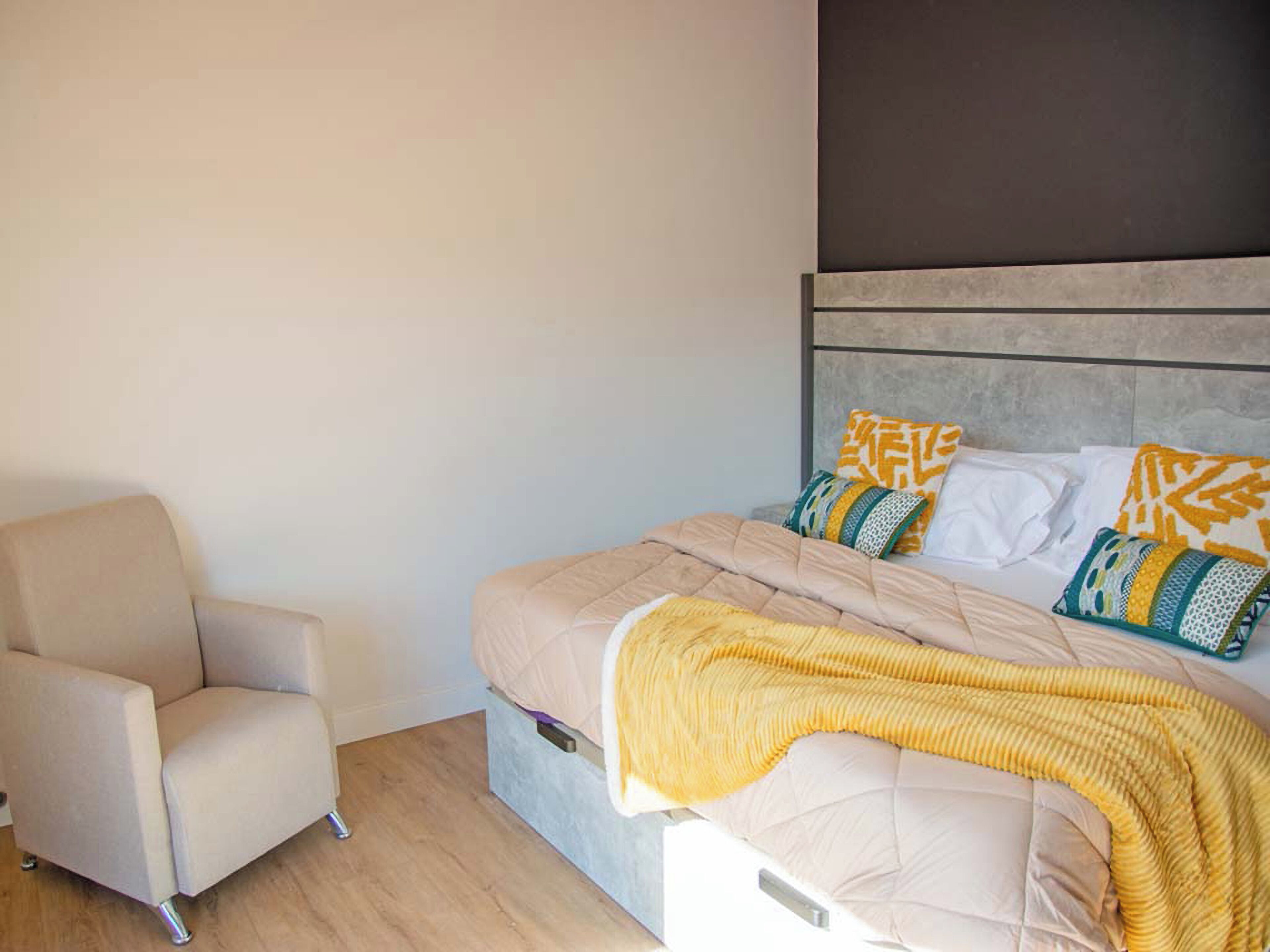 A bedroom with a bed, a chair, and a headboard.