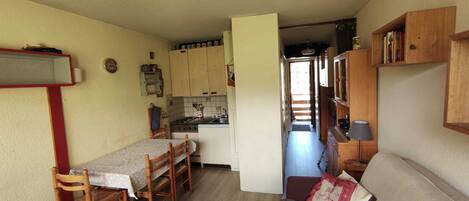 Un espace de vie compact comprenant un coin repas, une kitchenette et un canapé.