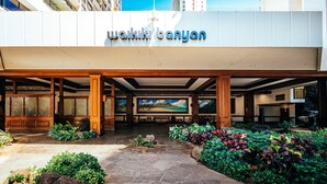 A hotel entrance with a stone pathway, wooden pillars, and a mural of a landscape.