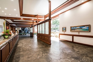 Um hall com piso de pedra, painéis de madeira e obras de arte nas paredes.