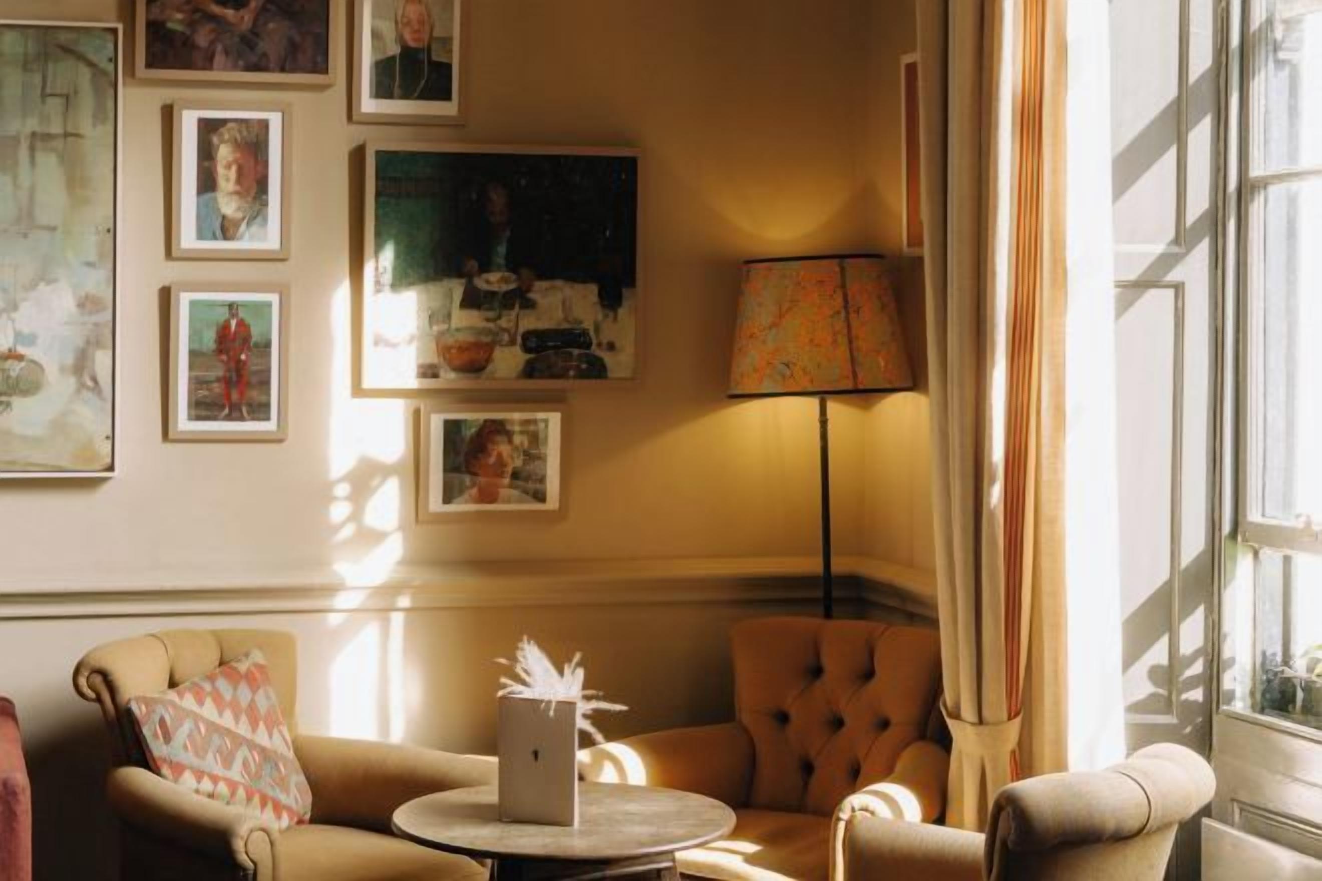 A room with a sofa, a chair, a lamp, and framed pictures on the wall.