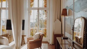 Una habitación con un ventanal grande, una silla, una lámpara y un espejo.