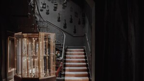 Una escalera con una pared oscura y una vitrina de vidrio que contiene varios objetos.