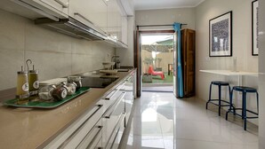 Una cocina moderna con estufa de acero inoxidable, salpicadero de vidrio y puerta corrediza que da a un patio.