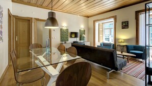 Una sala de estar moderna con una mesa de comedor de vidrio, sillas de madera, un sofá y un televisor.