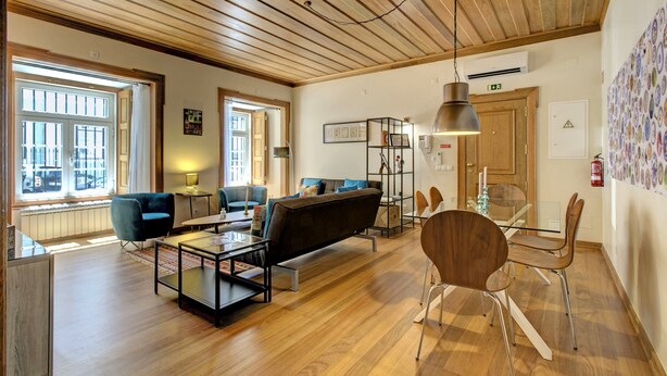 Una sala de estar moderna con piso de madera, un sofá, una mesa de centro y un comedor con sillas y una mesa de vidrio.