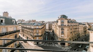 A cityscape with historic buildings, a street intersection, and a pedestrian crossing. - A STRIKING SUNLIT HAUSSMANN PENTHOUSE- LUXURY LIVING IN MONCEAU CHAMPS ELYSEES (Paris)