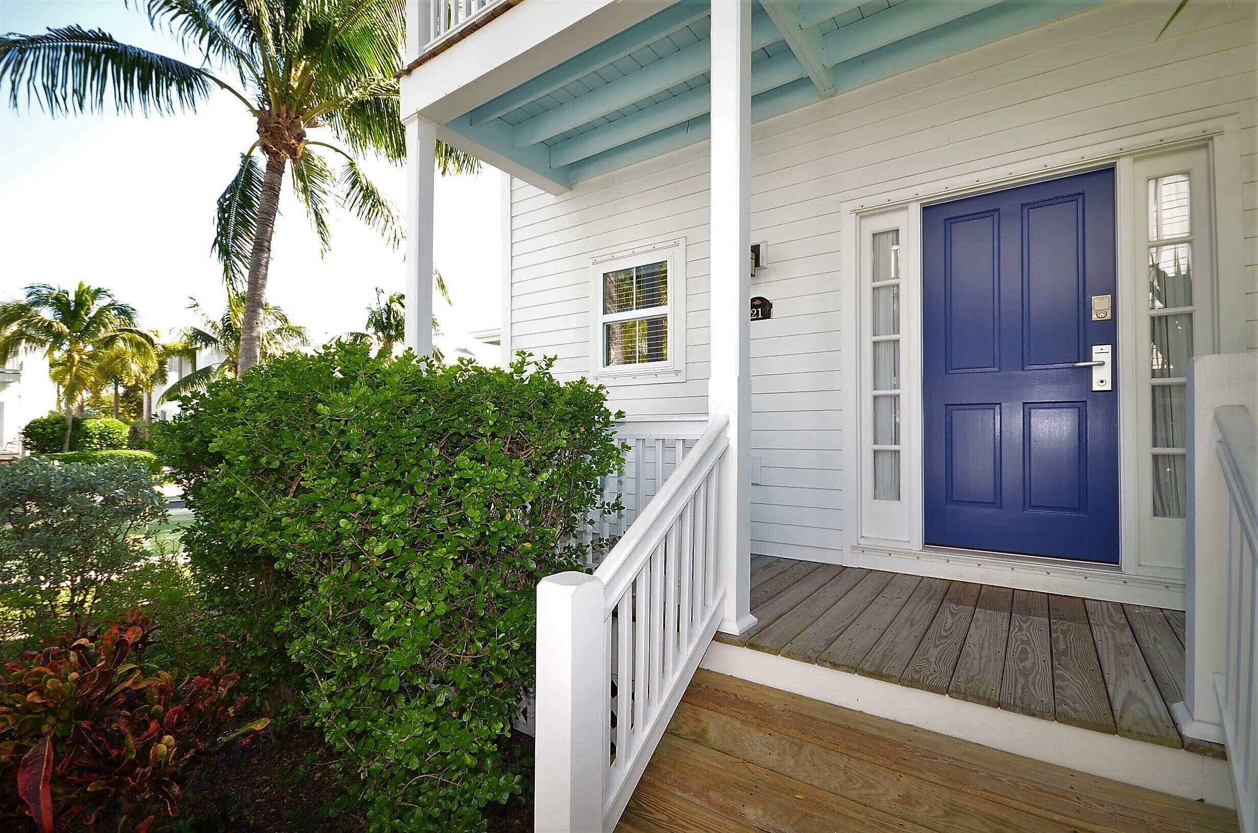 A white house with a blue door, a porch, and a small window.
