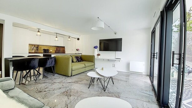 Una sala de estar moderna con un sofá, comedor y un televisor montado en la pared.