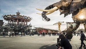 Un carrusel, un elefante mecánico grande y un edificio con techo rojo.