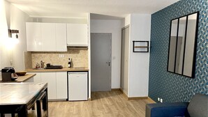 Ett kompakt bostadsutrymme med ett litet kök, en matplats och en sittgrupp.