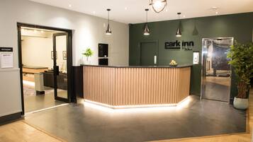 Una recepción de diseño moderno, un cartel que dice 'Park Inn' y una planta en maceta.