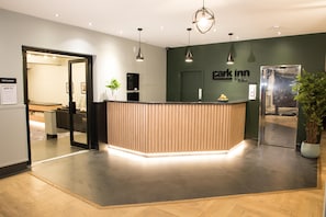A reception desk with a modern design, a sign for 'park inn', and a potted plant.