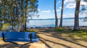 A bench by a lakeside with trees and a clear view of the water. - Peaceful Waterfront  by Book Jervis Bay - wheelchair accessible - Stunning Location for Family Holiday (Sanctuary Point)